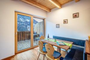 a dining room with a table and chairs and a balcony at Kreuzplonhof Apt Dorfblick in Luson