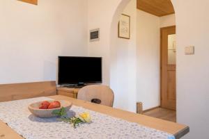 a table with a bowl of fruit and a television at Ronacherhof Apt Ringelblume in Collalbo