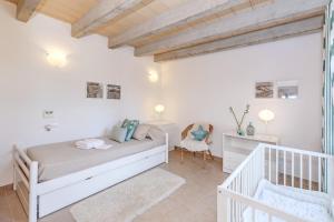 a white bedroom with a bed and a chair at Finca Sa Pradera in Palma De Mallorca