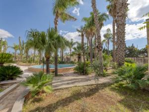 a swimming pool surrounded by palm trees at Villa Bludea - Salento in Torre Lapillo