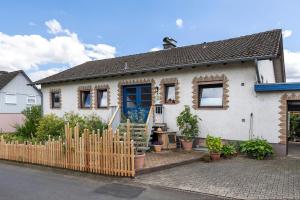 ein weißes Haus mit einem Zaun davor in der Unterkunft Ferienwohnung Schwalm - Aue in Neuental