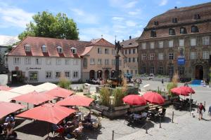 a group of people sitting under red umbrellas in a courtyard at Ferienwohnungen Hensler in Lindau