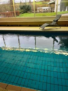 a swimming pool with a chair in the water at Ferienhof Riekeshof in Schmallenberg