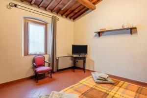a room with a bed a chair and a television at Bella Toscana Relax in Monsummano Terme