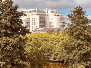 a tall white building with trees in front of it at Moin Mehrblick in Schillig