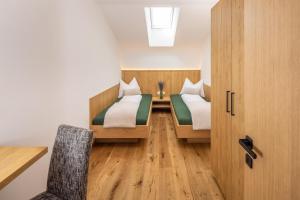 two beds in a room with a table and a chair at Zum Sonnentor App Pinus in Lutago
