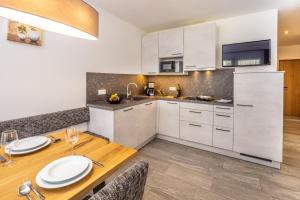 a kitchen with white cabinets and a wooden table at Zum Sonnentor App Pinus in Lutago