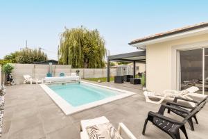 a backyard with a swimming pool and chairs and a house at Villa bassin d´archachon in Arès