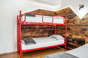 two red bunk beds in a room with a wooden wall at Appartamenti Ride Home in Commezzadura