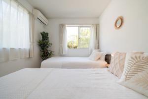 two beds in a room with a window at 照間Terumaの美しい海Mareまで徒歩30秒リビング広々快適 TERUMAREテルマーレ in Uruma