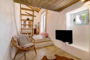 a living room with a tv and a chair at Casa Burro in Moncarapacho