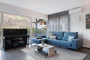 a living room with a blue couch and a piano at New Opening Vinea Guesthouse in Cornedo all'Isarco