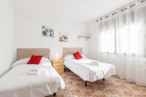 two beds in a room with white walls and red pillows at Villa Julia in Rubí