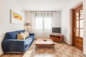a living room with a blue couch and a tv at Villa Julia in Rubí