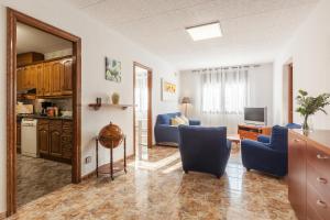 a living room with two blue chairs and a television at Villa Julia in Rubí +14 photos