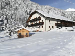 a building covered in snow in front of a mountain at Pfaffingerhof Antholz in Masserie