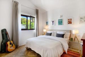 a white bedroom with a bed and a guitar at Casa Carmen - Comfort and Privacy in Nazaret +25 photos