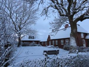 a snow covered yard with a bench in front of a building at Große Warf mit Rasenfläche in Ockholm