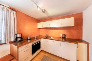 a kitchen with white cabinets and an orange wall at Florerhof Ferienwohnung Rose in Vols am Schlern +17 photos