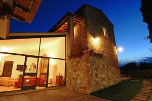 a house with a stone wall and windows at night at Villa Arnilù in San Gimignano