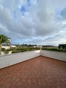 a balcony with a brick floor and a white wall at Dall'alba al Tramonto in Alezio