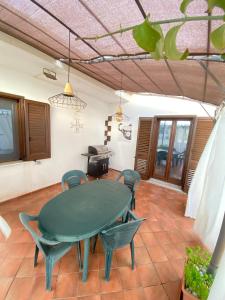 a dining room with a green table and chairs at Dall'alba al Tramonto in Alezio
