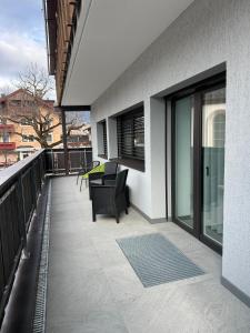 a balcony with a black chair on a building at Mountain Meadows Apt 2 in Valdaora