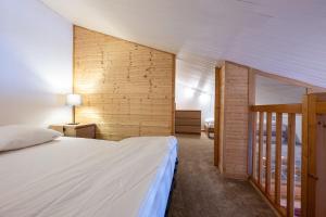 a bedroom with a white bed and a wooden wall at Lauziere dessus 50 in Valmorel