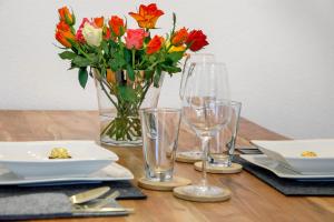 a wooden table with a vase of flowers and glasses at Waldmariechen in Neresheim