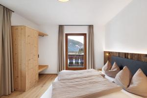 a bedroom with two beds and a window at Pfaffingerhof Antholz in Masserie