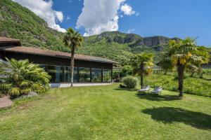 a house with palm trees and mountains in the background at Thanhammer Apt Quarz in Terlano