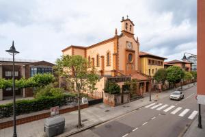 an old church with a clock tower on a street at Little Yellow House in Gijón