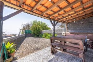 a wooden bench sitting under a wooden pergola at Casa de Campo Serrão in Calheta
