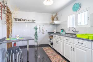 a kitchen with white cabinets and a sink and a table at Casa de Campo Serrão in Calheta