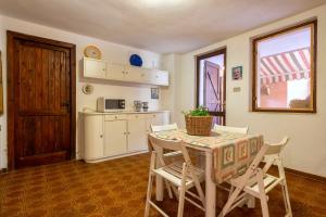 a dining room with a table and chairs and a kitchen at Casa al mare con ampia veranda in Stintino
