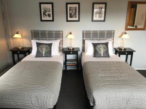 two beds in a room with two lamps at Troldhaugen Lodge - Adults Only in Jindabyne