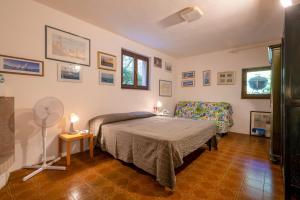 a bedroom with a bed and a chair and a fan at Casa al mare con ampia veranda in Stintino