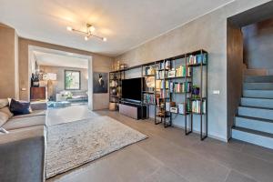 a living room with a couch and a tv and book shelves at Villa Artista in Gardone Riviera