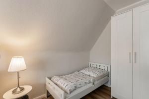a white bedroom with a bed and a lamp at Ferienhaus Nilsson in Heide