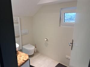a white bathroom with a toilet and a window at Zimmer in Müsch nahe Nürburgring in Müsch