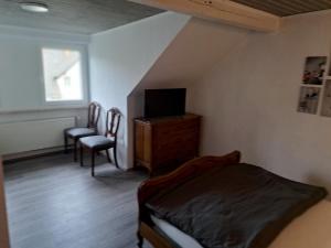 a bedroom with a bed and a tv and chairs at Zimmer in Müsch nahe Nürburgring in Müsch