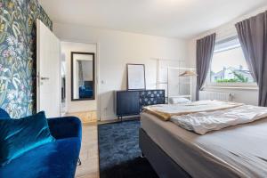 a bedroom with a bed and a blue chair at Penthouse Kokorey in Halstenbek