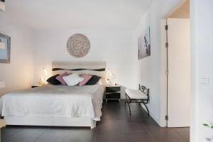 a white bedroom with a bed and a chair at The Garden Secret in Villaverde +23 photos