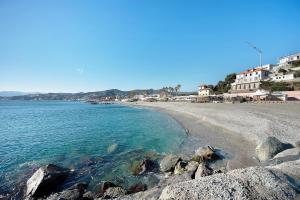 a beach with rocks in the water and buildings at Il Corallo in Albisola Superiore
