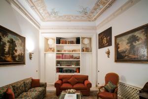a living room with a couch and chairs and a book shelf at Palazzo P D'ajmo - Dimora Storica in Lecce
