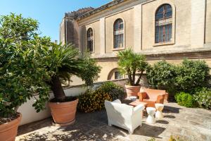 a courtyard with chairs and trees in front of a building at Palazzo P D'ajmo - Dimora Storica in Lecce