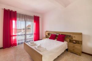 a bedroom with a large bed with red curtains at Casa Guerreiro in Branqueira