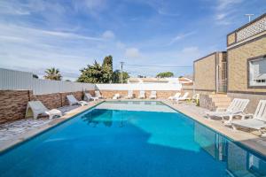 a swimming pool with white lounge chairs and a house at T2 Anastácio com vista Jardim in Olhos de Água