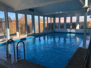 a large indoor swimming pool with blue water and windows at Ferienwohnung Borkum in Burhave