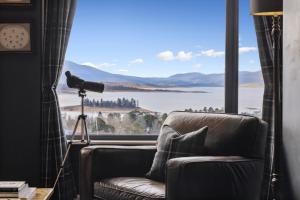 a living room with a couch and a large window at Troldhaugen Lodge - Adults Only in Jindabyne